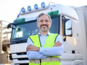 transportista mayor posando junto a su camión